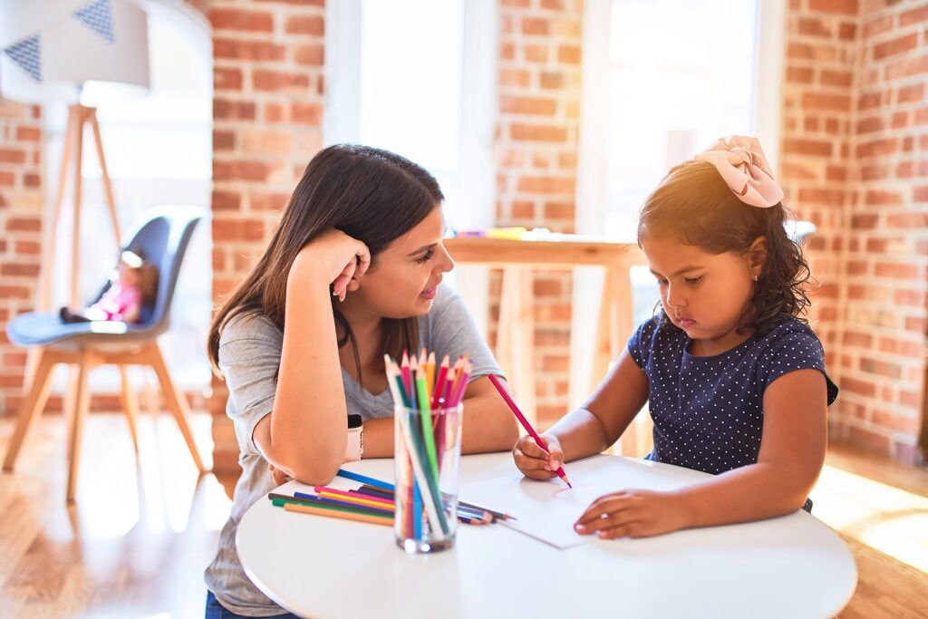 a young ABA therapist works with an autistic student in a small classroom